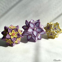 Three finished 3D FSL floral balls in lilac, purple and yellow thread color combinations