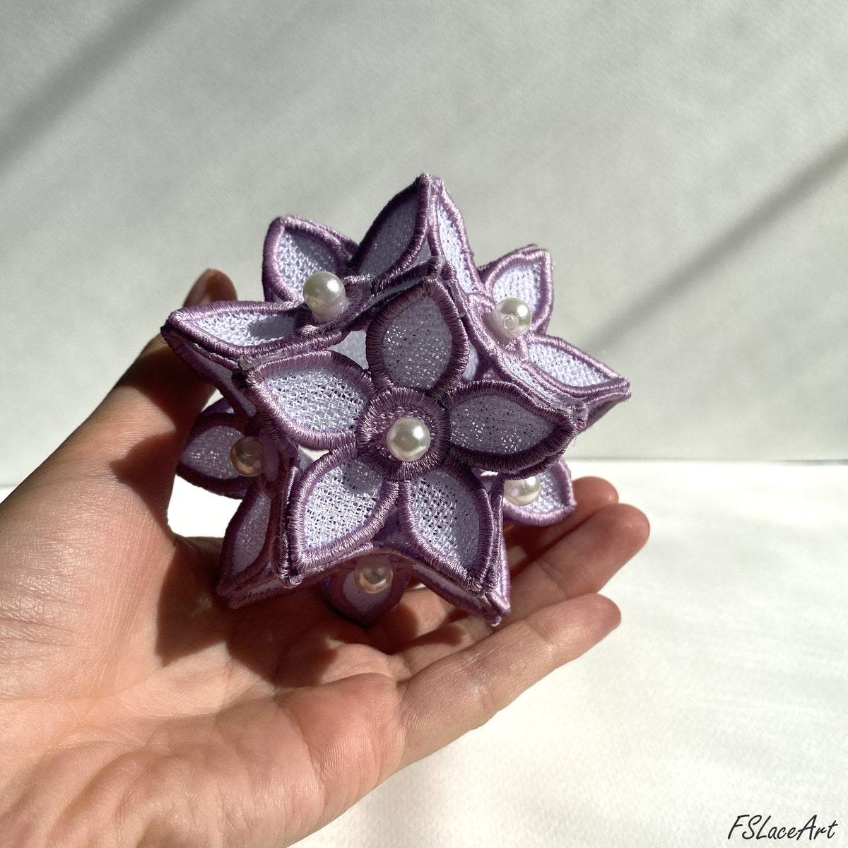 Finished lilac and white 3D FSL floral ball held in hand with layered flowers and pearl centers