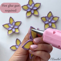 Hot glue gun joining yellow and lilac FSL flower pieces during 3D floral ball assembly