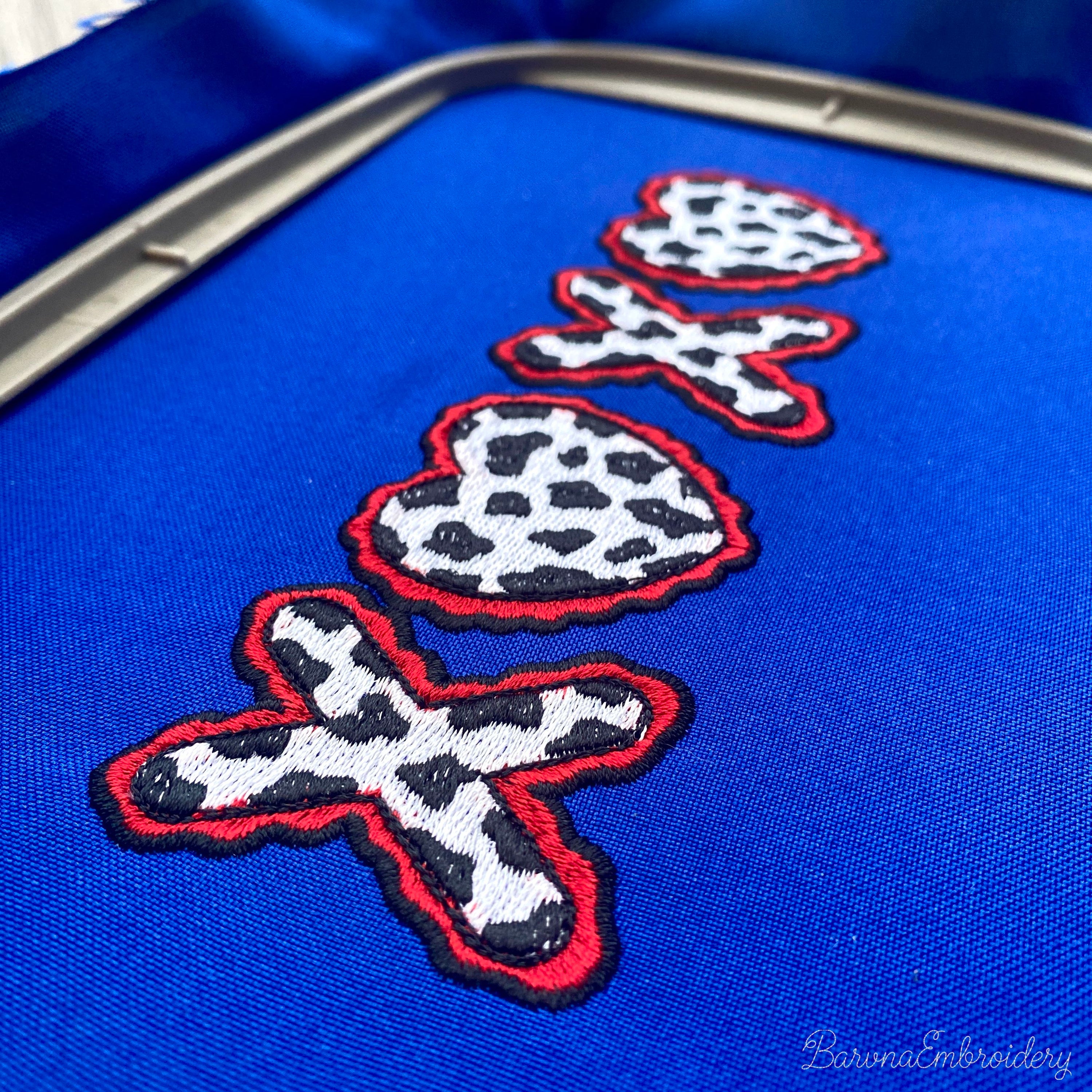 Machine embroidery design of the letters XOXO where both O characters are replaced by cow print hearts with wavy red borders.