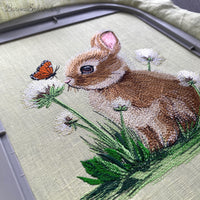 A collection of five high-quality machine embroidery designs: bunnies with butterflies, wildflowers, dandelions, and spring greenery in a realistic style.
