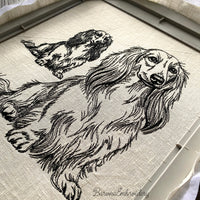 Long haired dachshund sitting upright single color embroidery design.