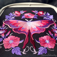 Pink and purple luna moth machine embroidery design surrounded by symmetrical flowers