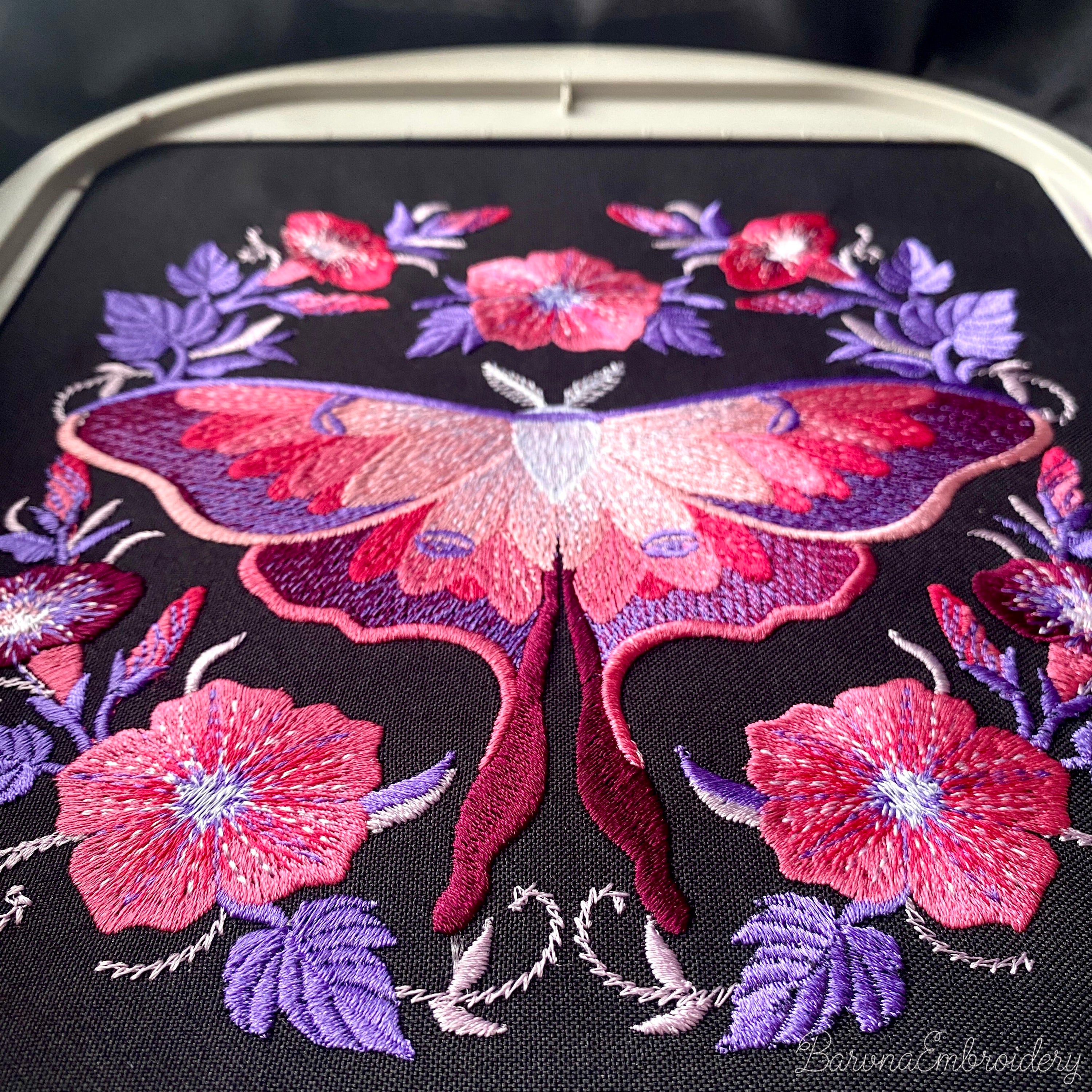 Pink and purple luna moth machine embroidery design surrounded by symmetrical flowers
