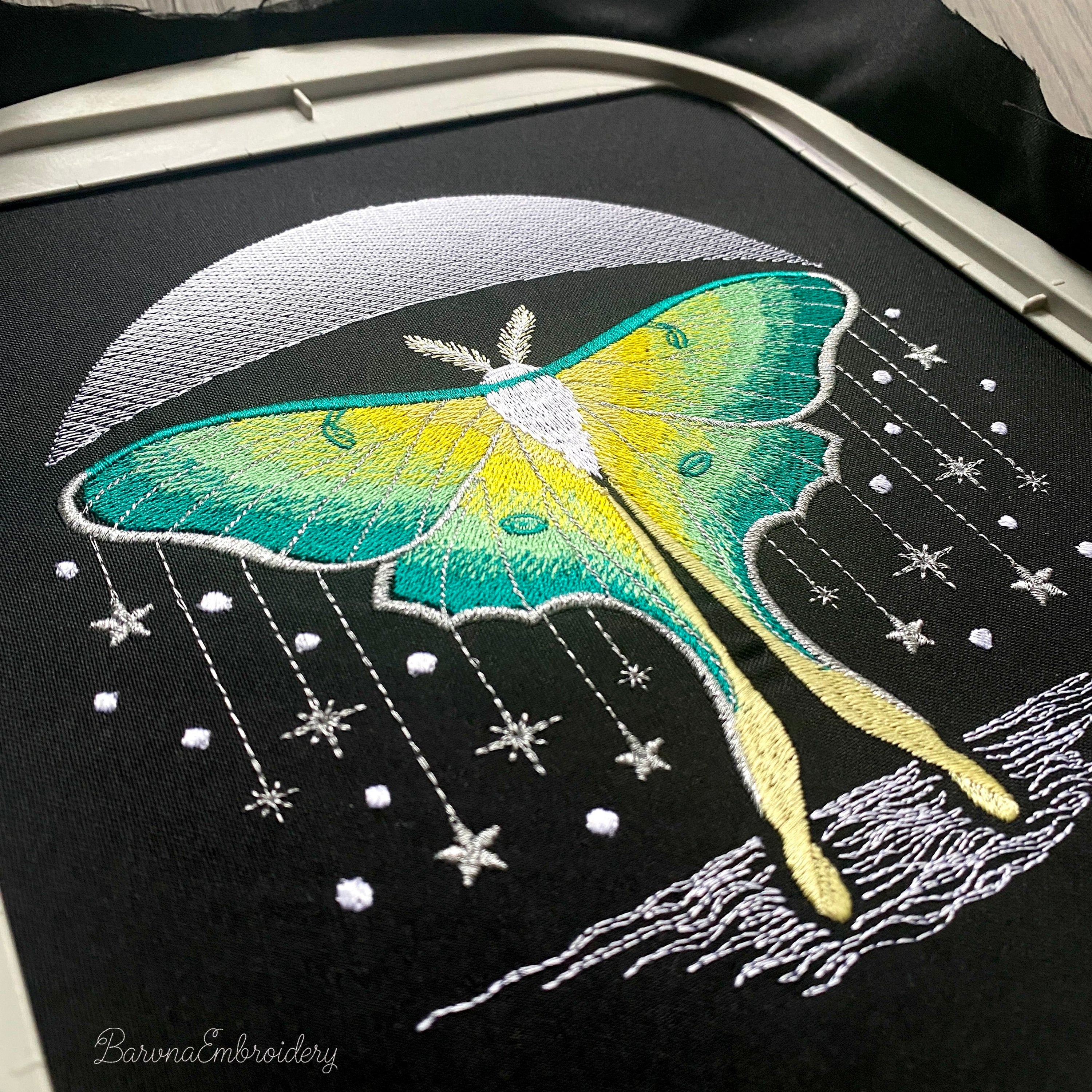 Green luna moth machine embroidery design positioned beneath crescent moon with stars