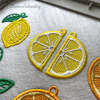 Three pairs of FSL lemon embroidery earrings — half-slice, whole lemon with green leaves, and round citrus slice — displayed on cream fabric, Free Standing Lace machine embroidery design.
