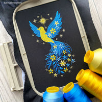 Blue and yellow flying bird embroidery design with stars and flowers trailing from wings – symbolic Ukrainian patriotic motif.