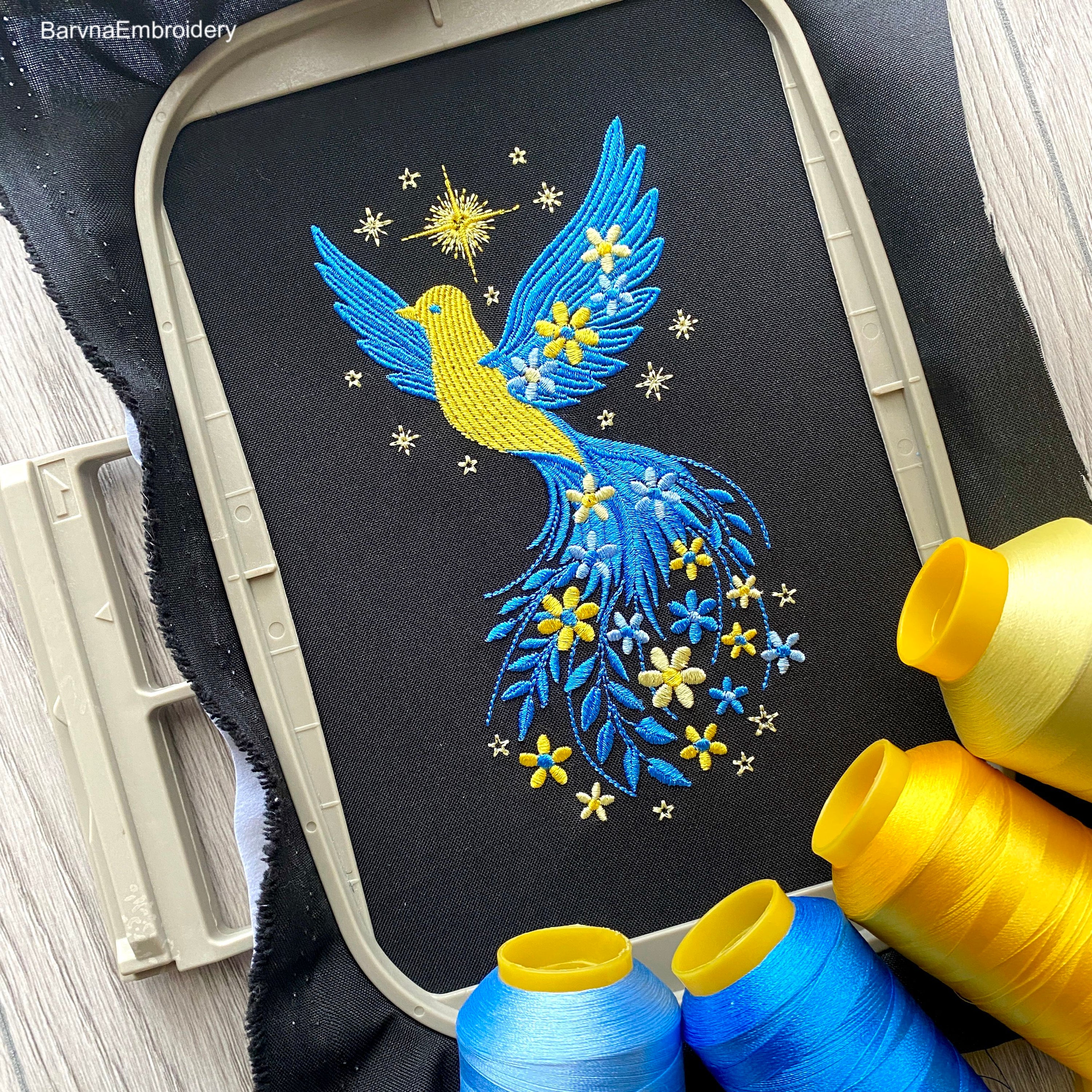 Blue and yellow flying bird embroidery design with stars and flowers trailing from wings – symbolic Ukrainian patriotic motif.