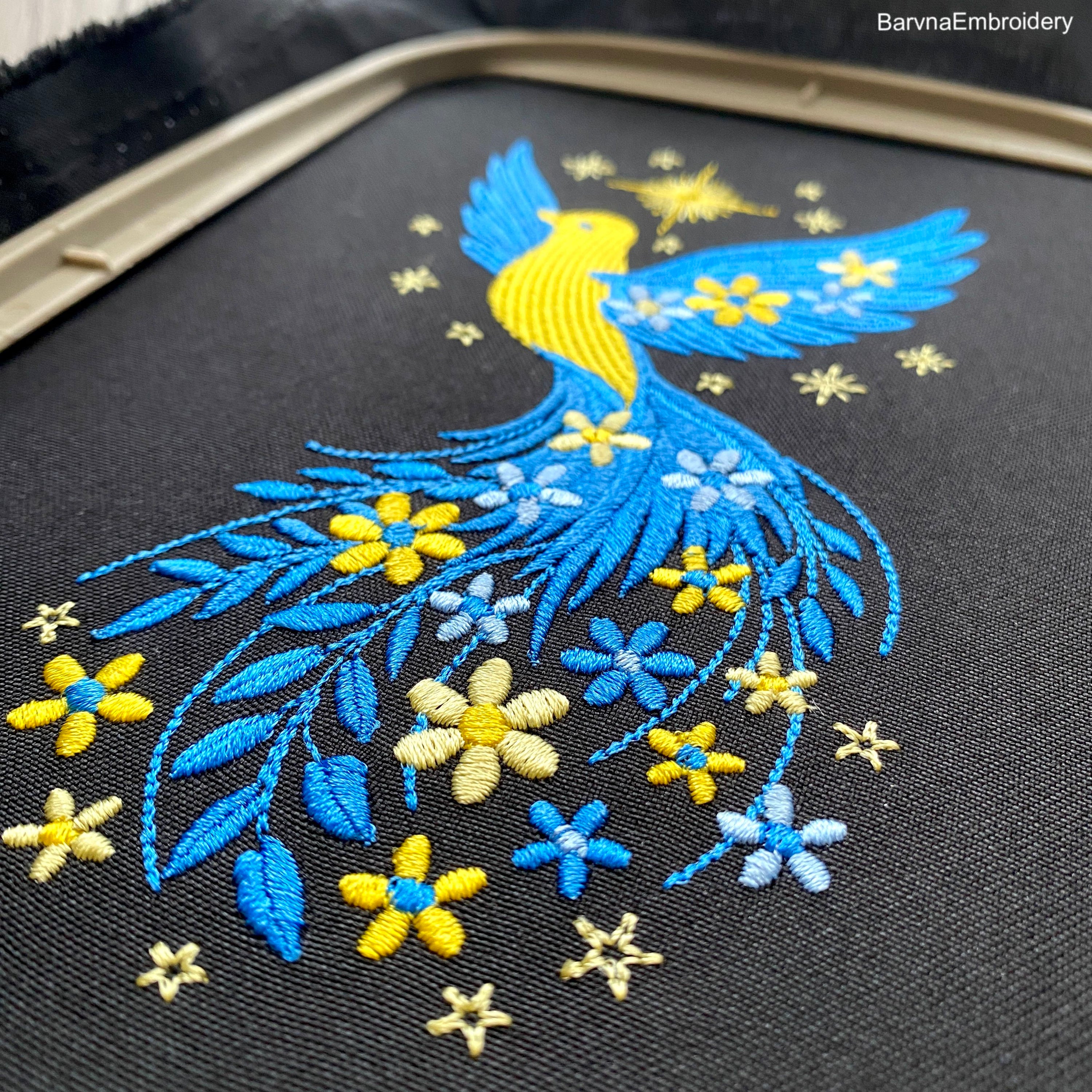 Blue and yellow flying bird embroidery design with stars and flowers trailing from wings – symbolic Ukrainian patriotic motif.