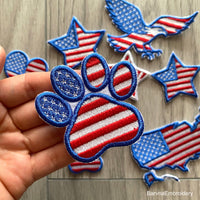 Machine embroidery design of a paw with the American flag inside, great for patriotic pet lovers.