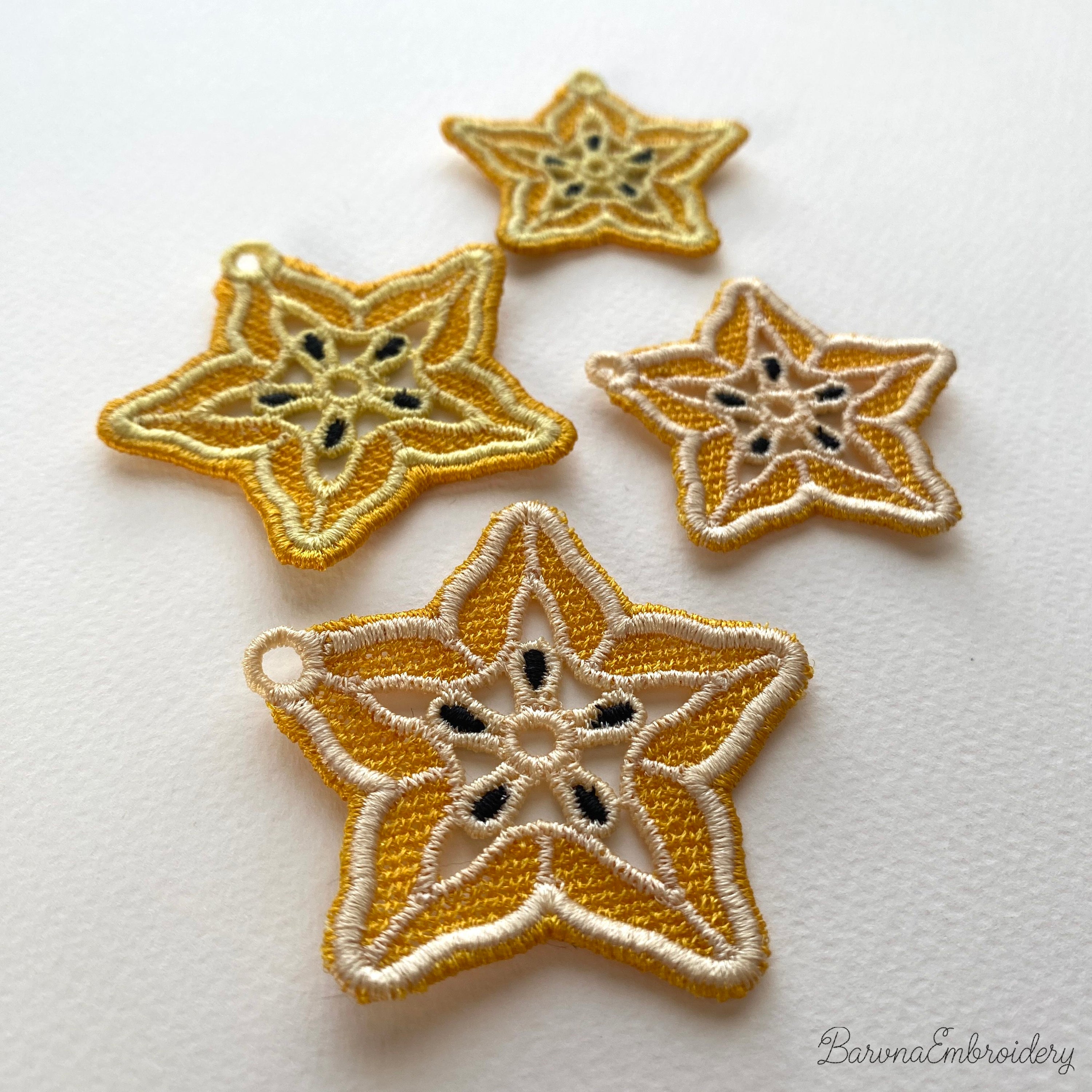 FSL carambola star fruit embroidery designs in two sizes — warm gold lace star shape with cream inner pattern and dark seed details — finished stitched results, Free Standing Lace machine embroidery pattern for earrings and pendants.