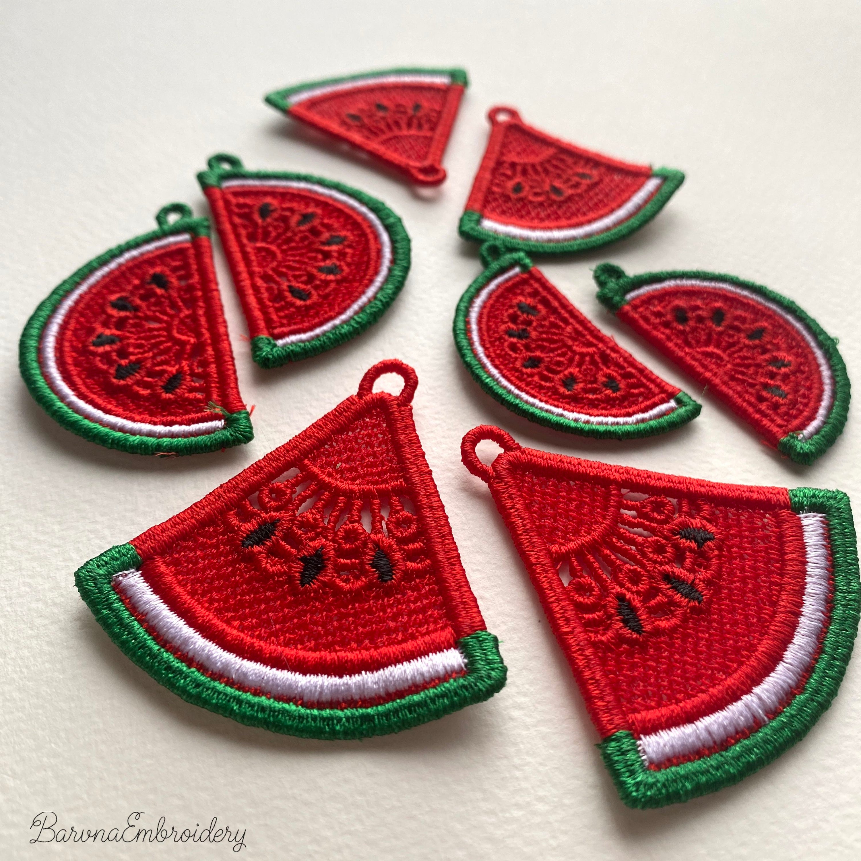Two mirrored FSL watermelon slice earrings — a machine embroidery design in Free Standing Lace technique, showing red lace fill, black seeds, and green border with a hanging loop.