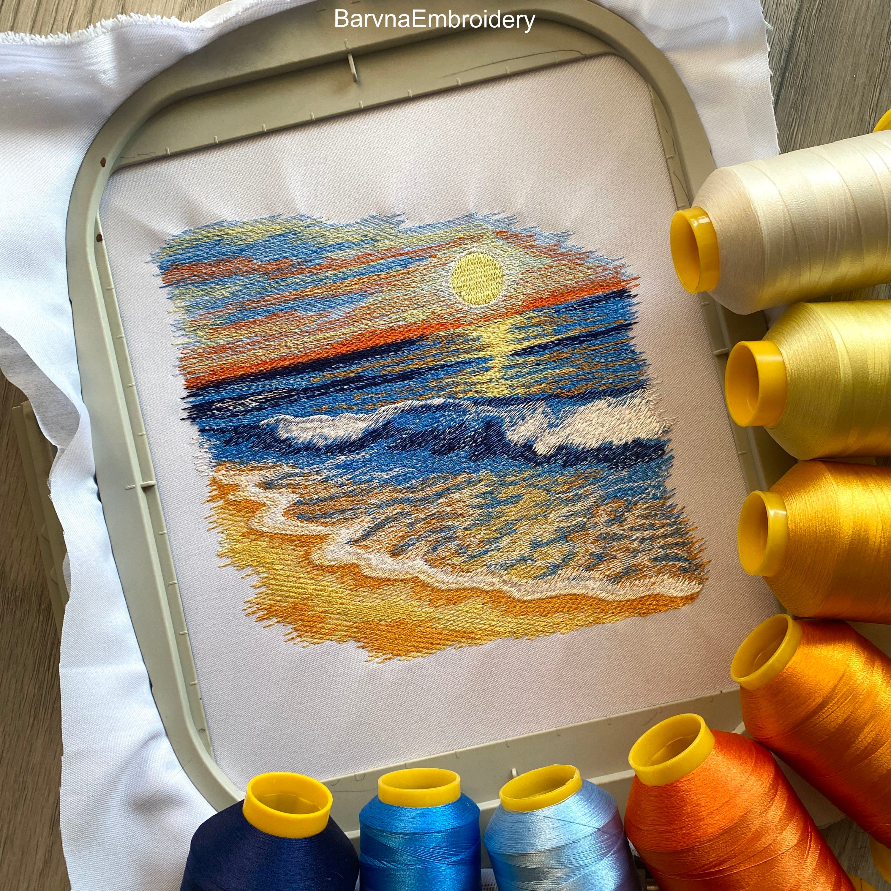 Machine embroidery design of a seaside landscape with golden sand, gentle ocean waves, and a vibrant sunset.