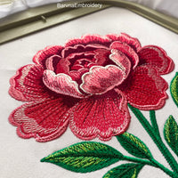 Machine embroidery design of a large pink peony flower with detailed stitching and green leaves, perfect for floral-themed projects and elegant decor.