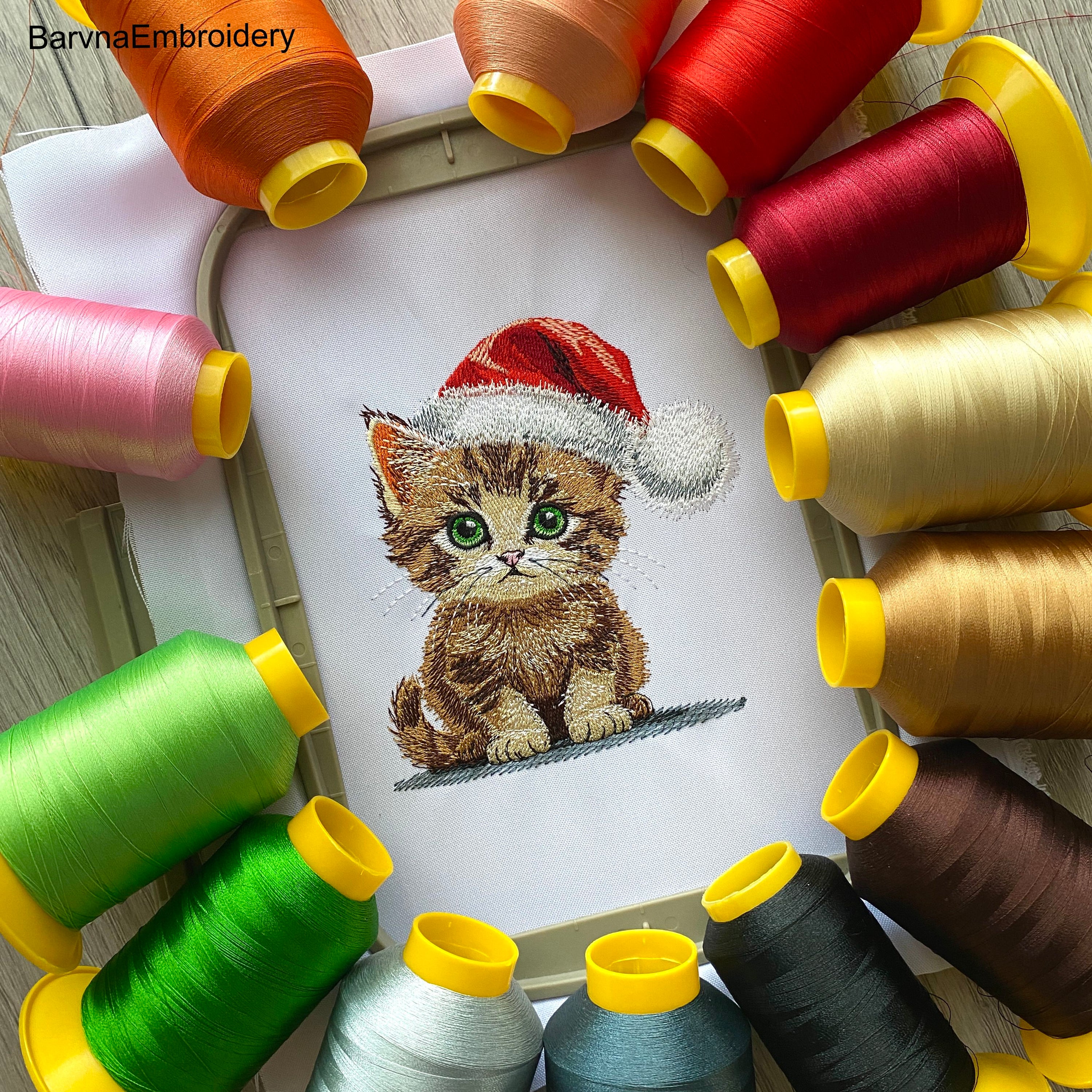 A realistic-style machine embroidery design of a cute kitten wearing a red Santa hat, perfect for Christmas-themed stitching.