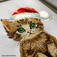 A realistic-style machine embroidery design of a cute kitten wearing a red Santa hat, perfect for Christmas-themed stitching.