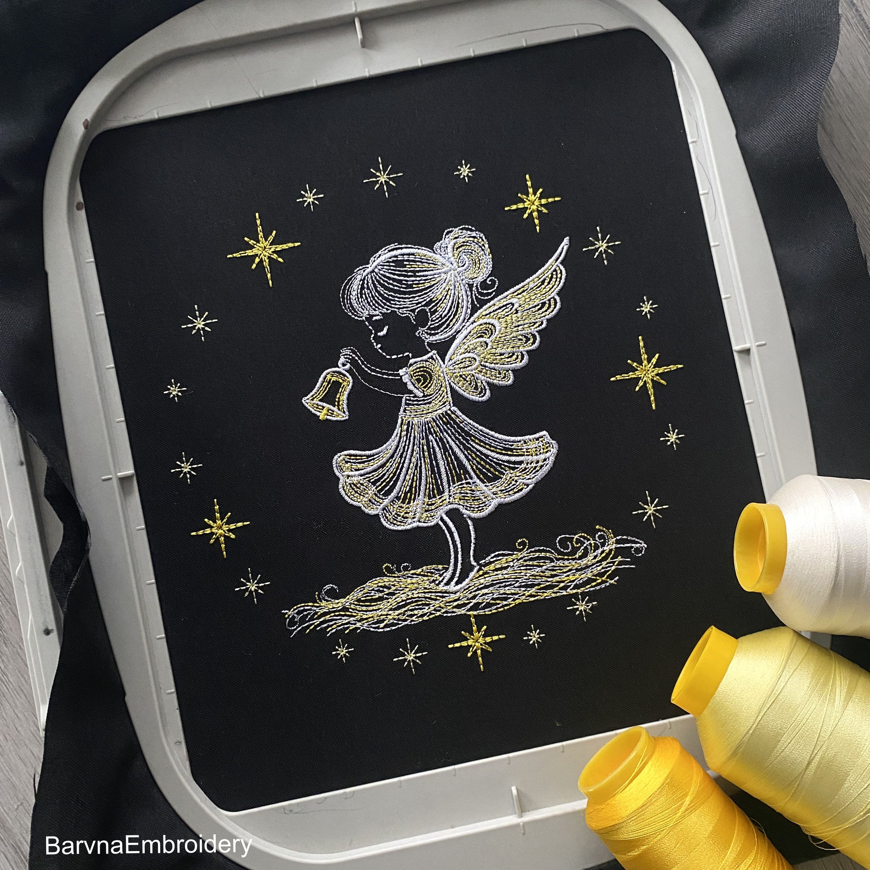 Christmas angel girl holding bell machine embroidery design with glowing stars and festive feel.