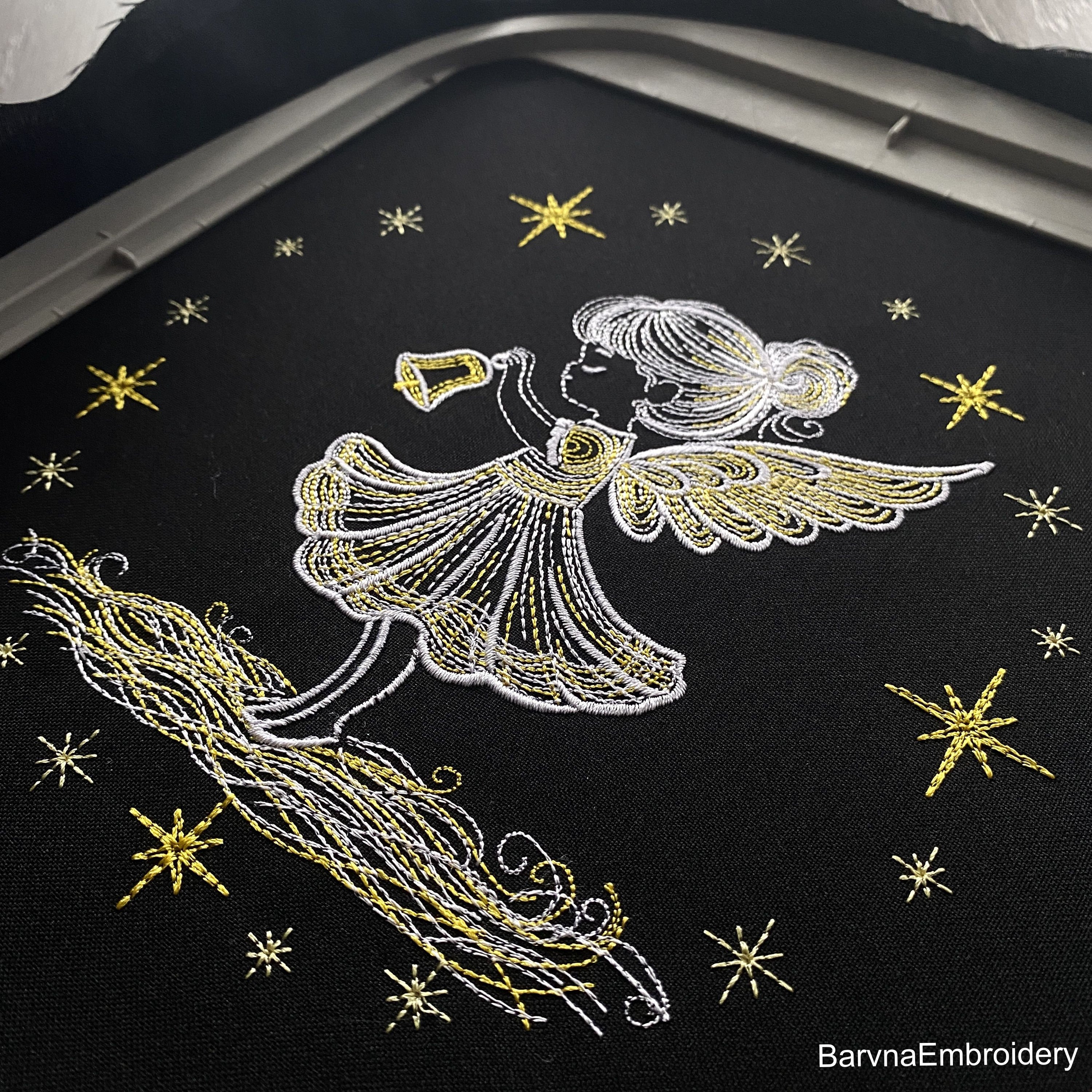 Christmas angel girl holding bell machine embroidery design with glowing stars and festive feel.