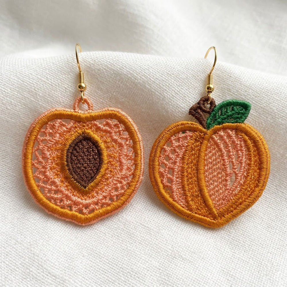 FSL peach embroidery designs in two styles — symmetrical peach half with stone center and whole peach with green leaf — shown as mirrored pairs, Free Standing Lace machine embroidery pattern for earrings and pendants.