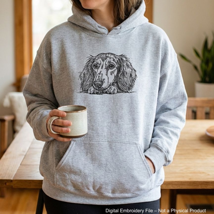 Black and white embroidered illustration of a long-haired dachshund dog. The dog is lying down, with its paws and head resting on a surface. The dog's eyes are open, and it has long, flowing fur.