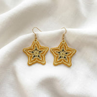 FSL carambola star fruit embroidery designs in two sizes — warm gold lace star shape with cream inner pattern and dark seed details — finished stitched results, Free Standing Lace machine embroidery pattern for earrings and pendants.