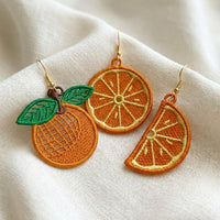 Three pairs of FSL orange embroidery designs — half-slice, whole orange with green leaves, and round citrus cross-section — Free Standing Lace machine embroidery pattern for earrings and pendants.