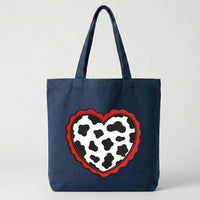 Machine embroidery design showing two versions of a cow print heart: one small filled and one large applique with a red wavy border.