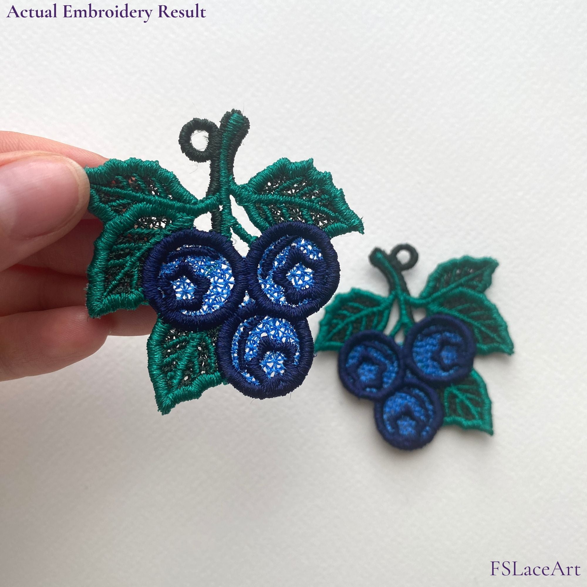 Two finished mirrored Blueberry FSL embroidery pieces with navy berries, green leaves and hanging loops