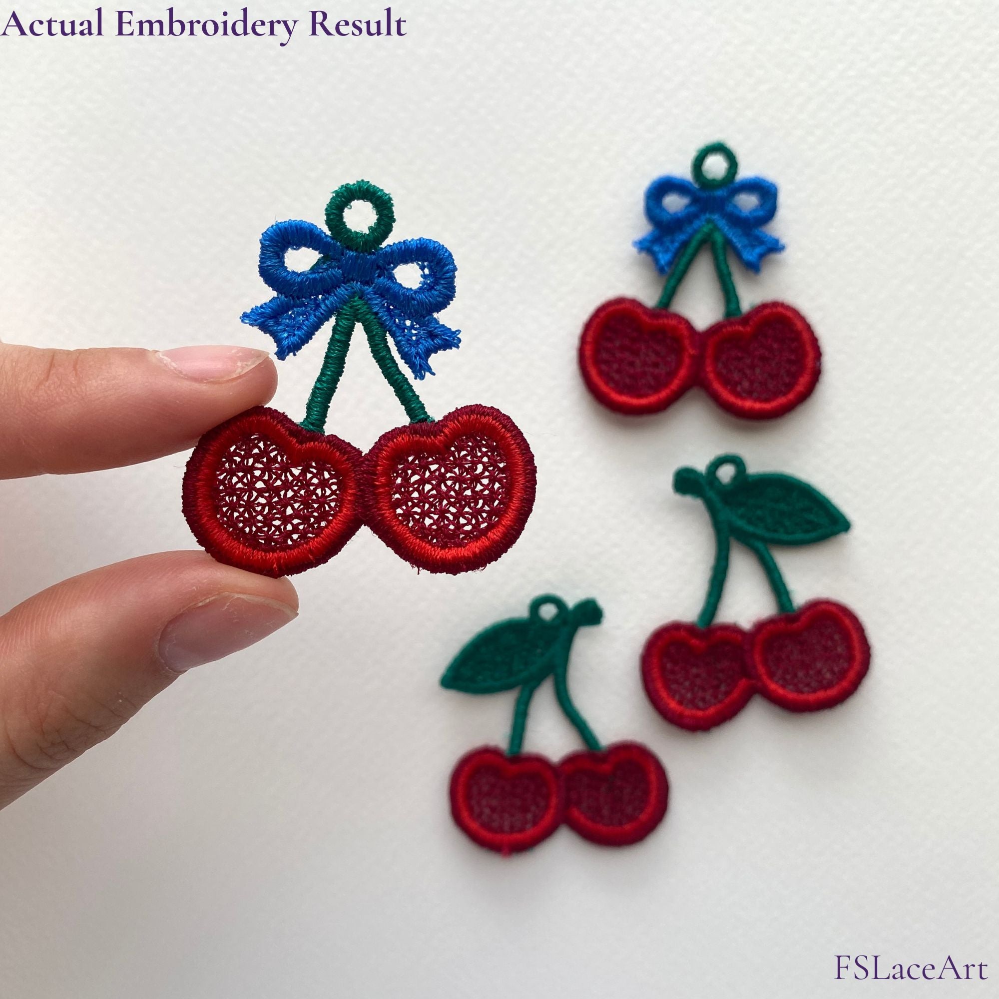 Hand holding an actual red cherry FSL stitch-out with blue bow; leaf variation shown in the background