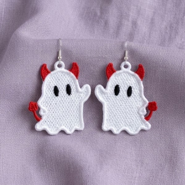 Pair of white Devil Ghost FSL earrings with red horns and curled tails displayed on lavender fabric