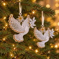 Two white and gold lace dove ornaments in different sizes hanging from ribbons on a Christmas tree with warm lights.