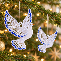 Two white lace dove ornaments with blue accents hanging on a Christmas tree with warm lights.