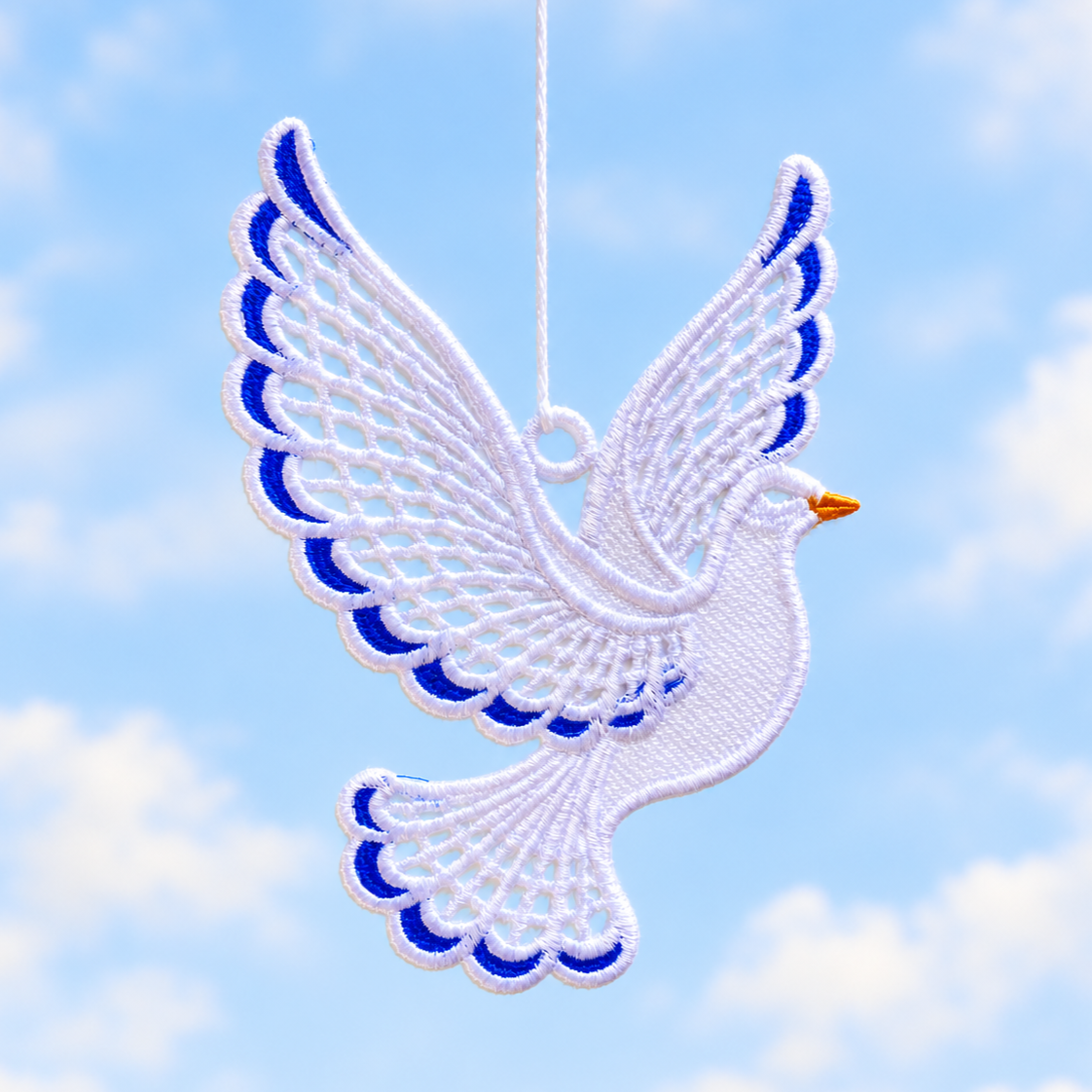 White and blue lace dove suspended against a blue sky, showing its outstretched wings, openwork tail and hanging loop.