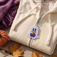 White lace ghost with a purple candy basket attached to a cream hoodie zipper, styled with autumn leaves and a pumpkin.