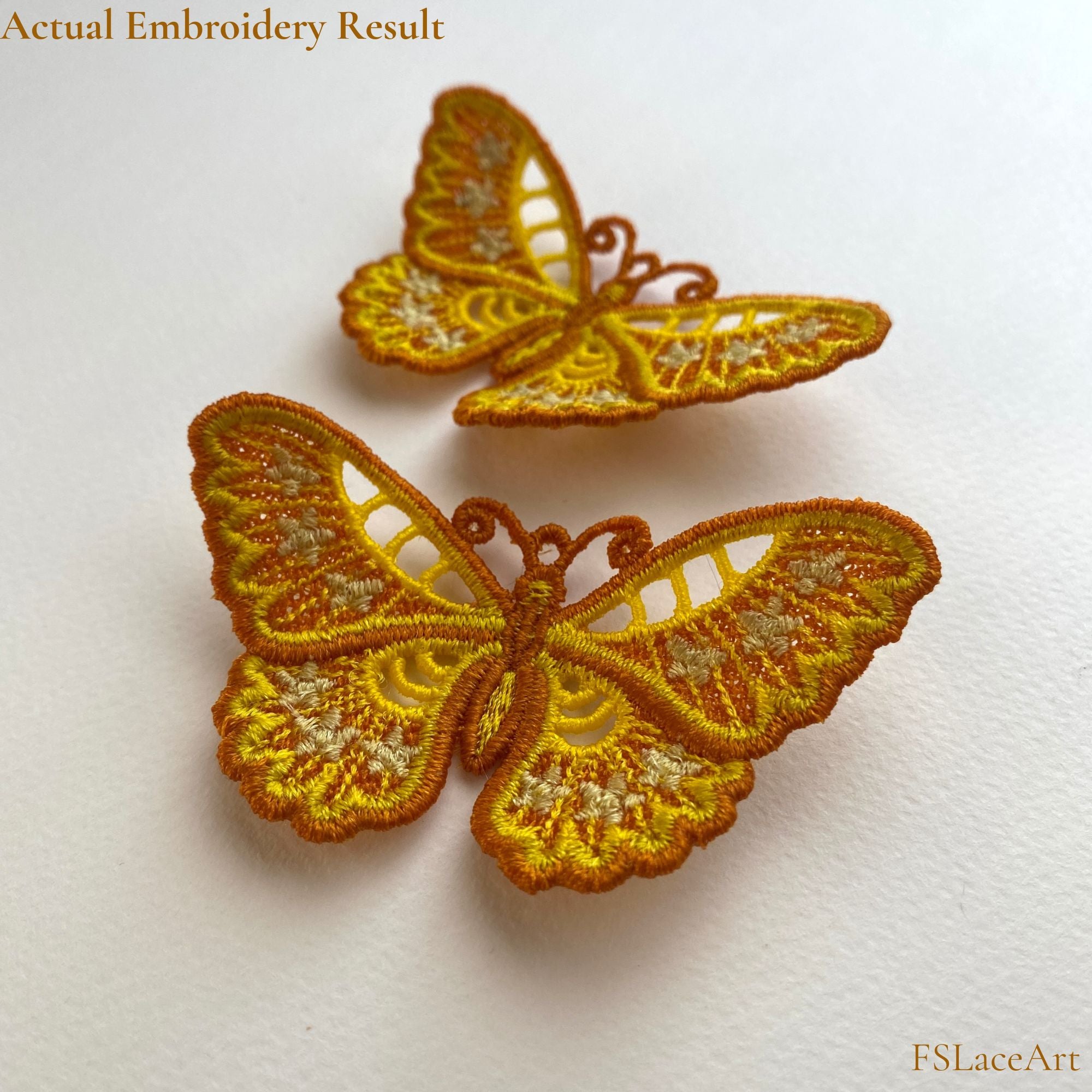 Two finished golden floral butterfly FSL stitch-outs displayed with raised wings