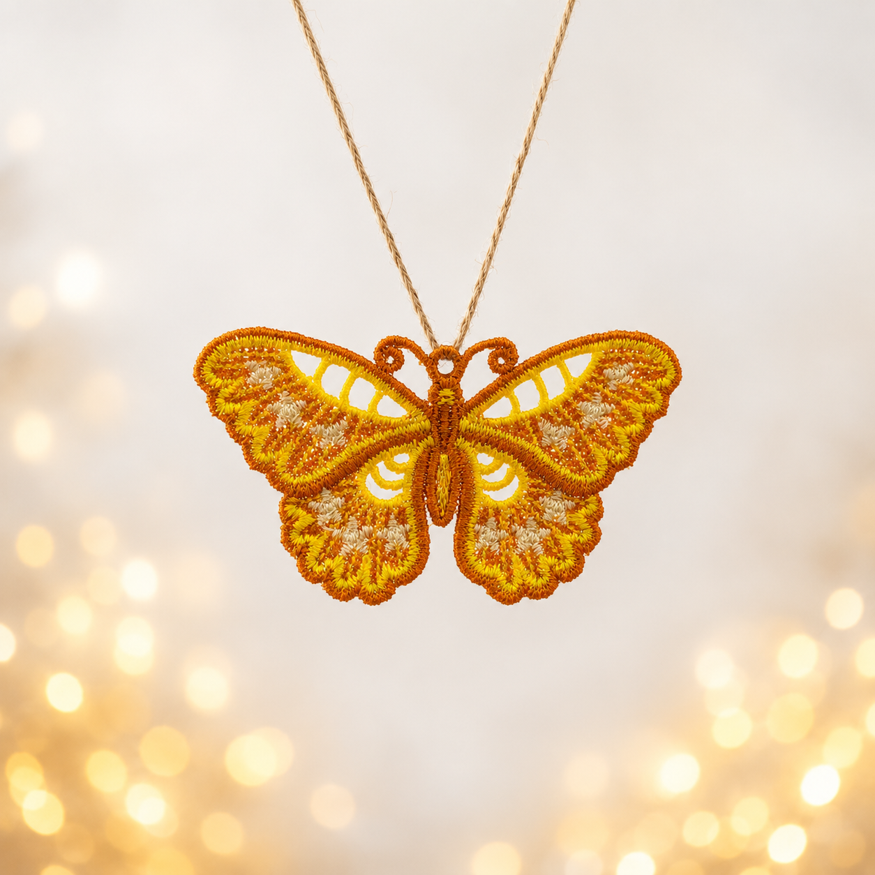 Golden floral butterfly FSL pendant with scalloped lace wings hanging from a natural cord