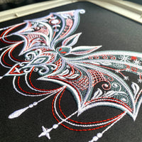 Close-up of actual gothic bat embroidery on black fabric, showing satin outlines, lattice stitching and red accents.