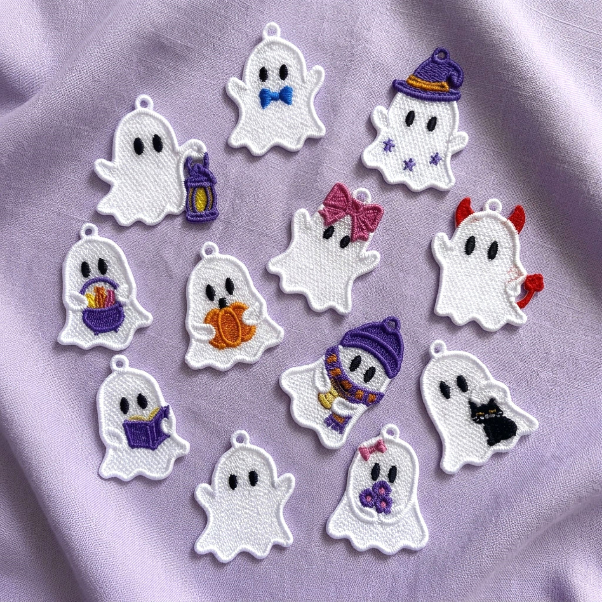 White freestanding lace Halloween ghosts on lavender fabric, featuring a book, coffee cup, candy basket, pumpkin, black cat and other colorful details.