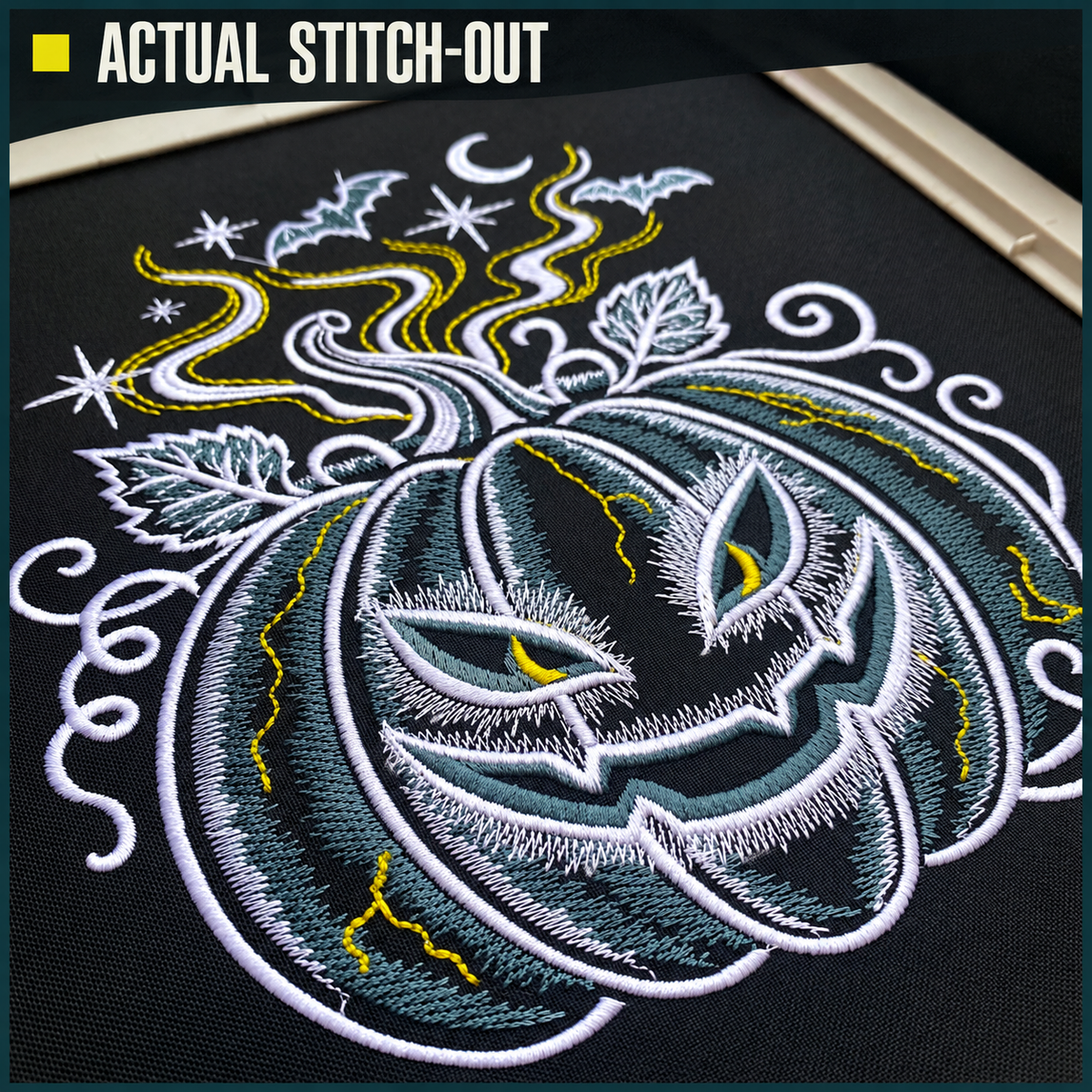 Close-up of actual Halloween pumpkin embroidery on black fabric, showing pale satin outlines, shaded stitching and yellow details.
