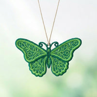 Green ornamental butterfly FSL pendant hanging from a natural cord, with leafy scrollwork inside its lace wings