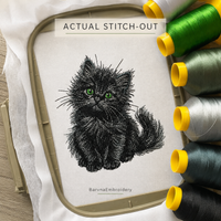 Black kitten embroidered on white fabric in a hoop beside green, gray, white and black thread spools.