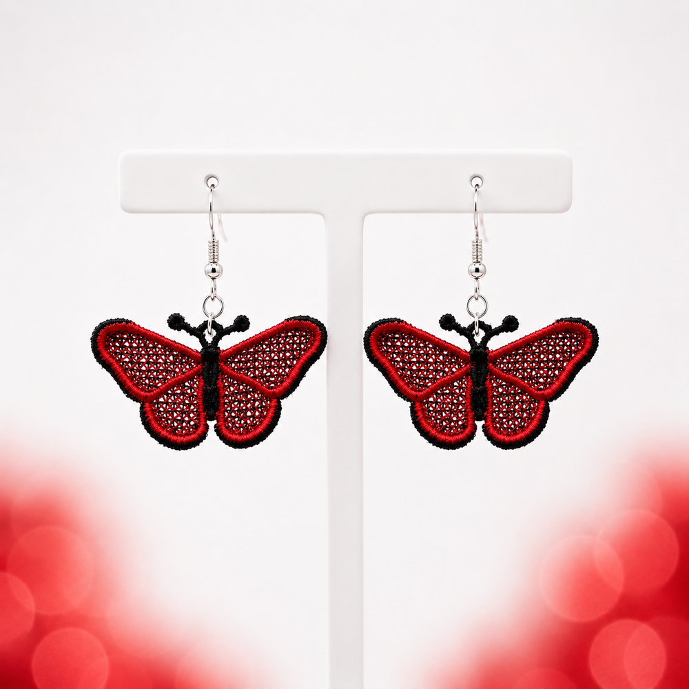 Pair of red and black butterfly FSL earrings with silver hooks displayed on a white jewelry stand