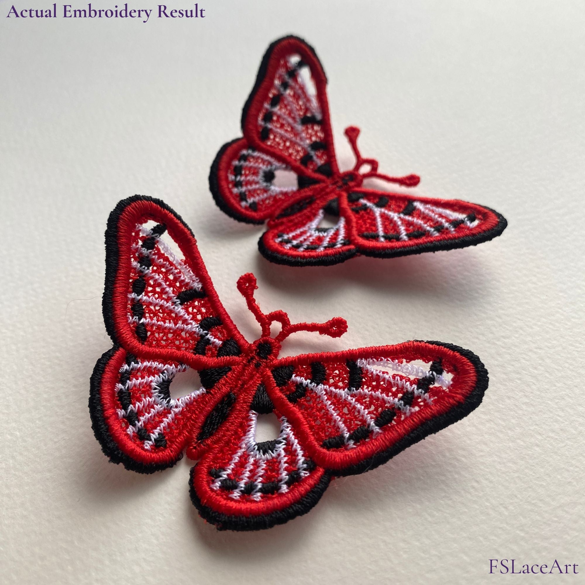 Two actual red, white and black spotted butterfly FSL stitch-outs displayed with raised wings
