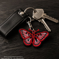 Red, white and black butterfly FSL keychain displayed beside silver keys and a black leather case