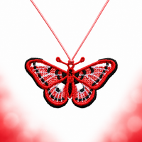 Red, white and black spotted butterfly FSL pendant hanging from a red cord against a white background