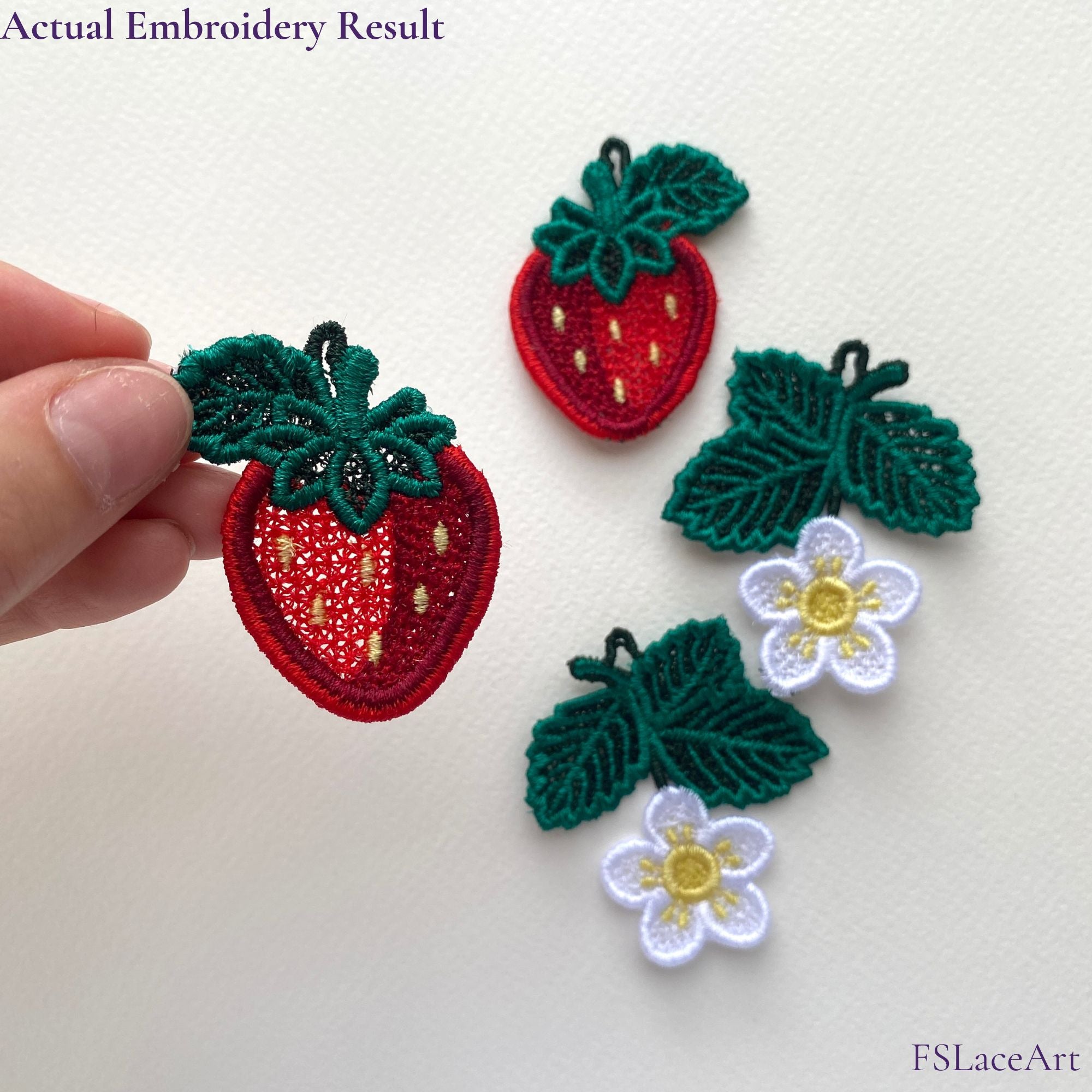 Hand holding an actual red strawberry FSL stitch-out with green leaves and yellow seed details