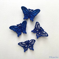 Four finished blue swallowtail butterfly FSL stitch-outs with open cutwork and lace-filled wings